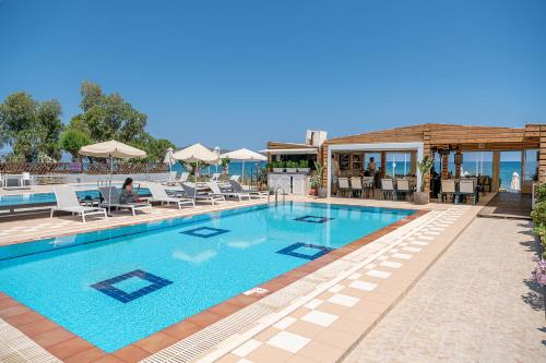 a pool at a resort with lounge chairs and umbrellas at Esperides Beach Hotel Apartments in Stalos