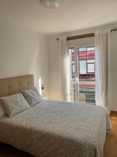 a bedroom with a large bed and a window at Apartamento N&S Carolinas in Vilagarcia de Arousa