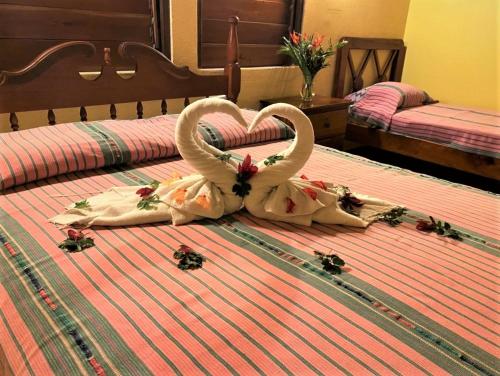 two swans are forming a heart on a bed at Crystal Paradise Resort in San Ignacio