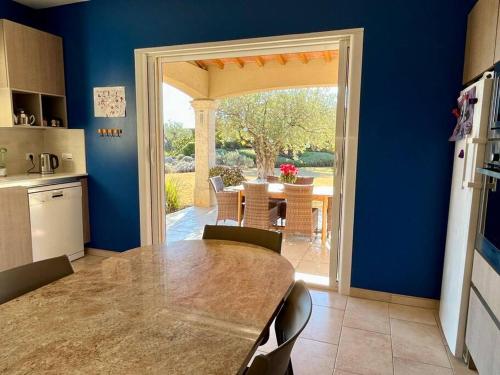 a kitchen with a table and an open door to a patio at Villa et piscine au jardin typique méditerranéen in Carros