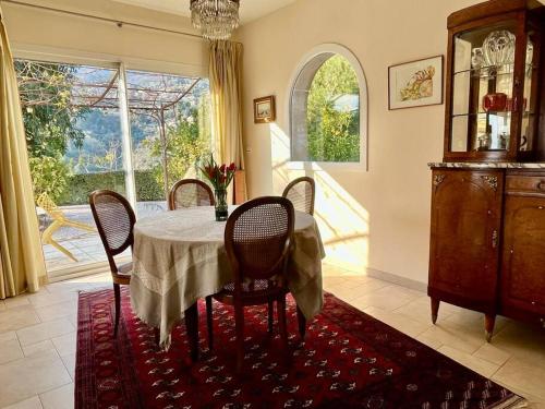 a dining room with a table and chairs and a window at Villa et piscine au jardin typique méditerranéen in Carros