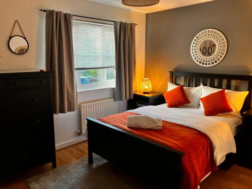 1 dormitorio con 1 cama grande con almohadas de color naranja y amarillo en Urban Escape Glasgow Green Free Parking 15min walk to City Center, en Glasgow