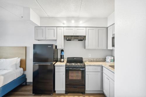 a kitchen with a black refrigerator and white cabinets at Sugar Sands Beachfront Hotel, a By The Sea Resort in Panama City Beach