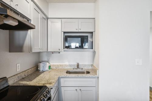 a kitchen with white cabinets and a sink at Sugar Sands Beachfront Hotel, a By The Sea Resort in Panama City Beach