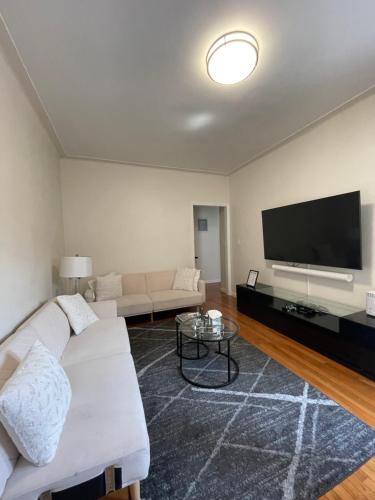 a living room with a white couch and a flat screen tv at 1BR Apt in Sunnyside 15 min to Manhattan in Woodside
