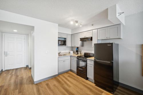a kitchen with white cabinets and a black refrigerator at Sugar Sands Beachfront Hotel, a By The Sea Resort in Panama City Beach