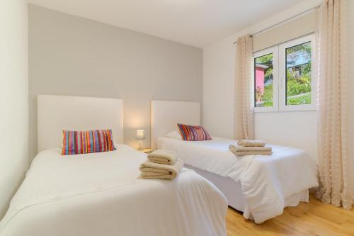 Duas camas num quarto com paredes brancas e janelas em Casa da Hortência do Faial no Faial