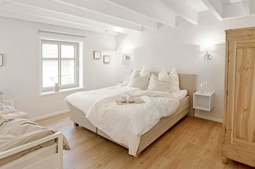 a white bedroom with a large bed and a window at Bi de Bark in Fehmarn