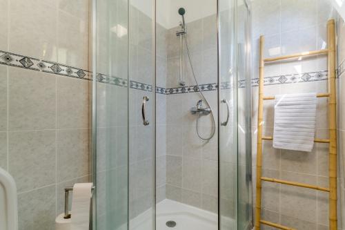 uma casa de banho com um chuveiro e uma porta de vidro em Casa da Hortência do Faial no Faial