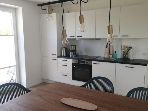 a kitchen with white cabinets and a wooden table with chairs at Kleenes Haffhus in Ueckermünde