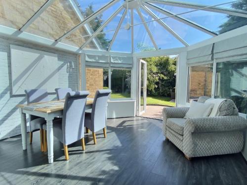 a conservatory with a table and chairs and a glass ceiling at Home in Solihull - Near NEC, BHX & Solihull Town Centre in Birmingham