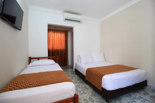 a hotel room with two beds and a television at Hotel Rodadero Inn By GEH Suites in Santa Marta