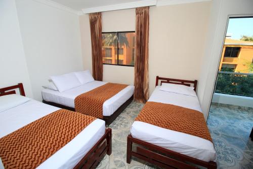 a hotel room with two beds and a window at Hotel Rodadero Inn By GEH Suites in Santa Marta
