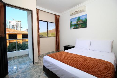 a bedroom with a bed and a large window at Hotel Rodadero Inn By GEH Suites in Santa Marta