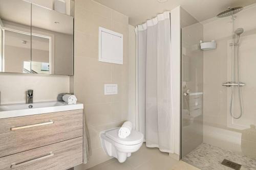 a white bathroom with a toilet and a shower at Dinbnb Apartments I Mid-City Luxury with Mini Balcony and Smart TV & Sound System in Bergen