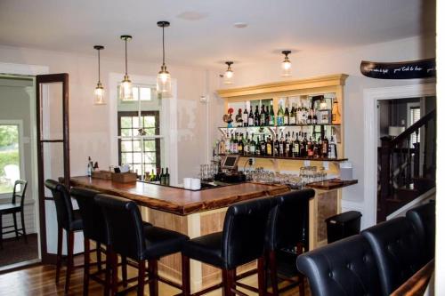 a bar with a wooden counter and black chairs at Sesuit Harbor House in East Dennis
