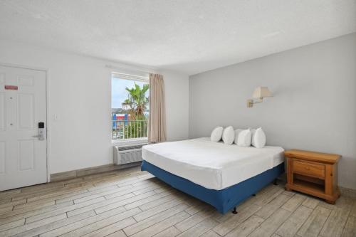 a white bedroom with a bed and a window at Holiday Terrace Beachfront Hotel, a By The Sea Resort in Panama City Beach