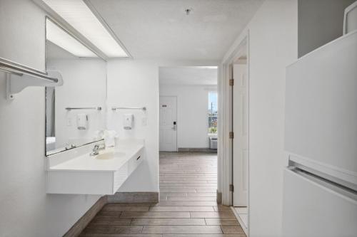 a white bathroom with two sinks and a mirror at Holiday Terrace Beachfront Hotel, a By The Sea Resort in Panama City Beach