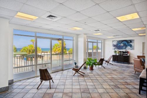 a waiting room with chairs and tables and windows at Holiday Terrace Beachfront Hotel, a By The Sea Resort in Panama City Beach