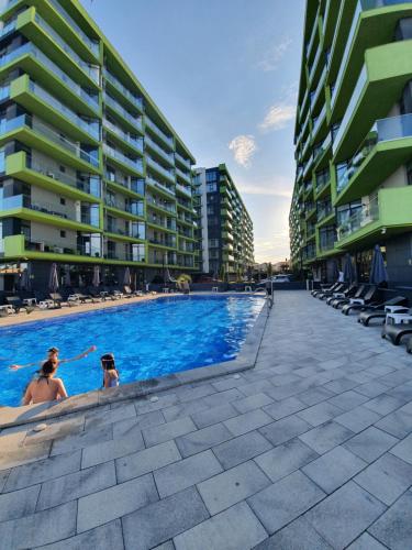 two people sitting in a swimming pool next to buildings at Sunway - Pool & Spa Beach Resort in Mamaia Sat/Năvodari