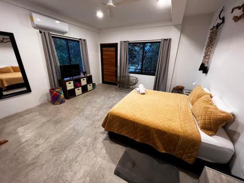 a bedroom with a bed and a couch and windows at Hostal Del Jaguar in Tulum