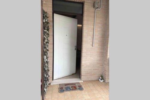 Eine weiße Tür in einem Backsteingebäude mit einer Katze daneben. in der Unterkunft Appartamento indipendente con terrazzo e giardino in Vasto