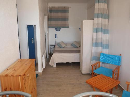 Habitación pequeña con cama y silla en Hôtel - Villa Les Sirènes, en Argelès-sur-Mer