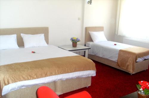 a hotel room with two beds and a red chair at Butik Ertur Hotel in Doğubayazıt