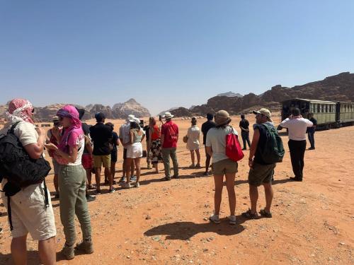 a group of people standing in front of a train at Yara camp in Wadi Rum