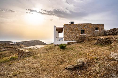 a stone house on a hill with the sun in the sky at Saint Nicholas Resort - Villas in Kithnos