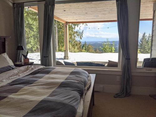 a bedroom with a bed in front of a large window at Mountain House of Wonder in Qualicum Beach