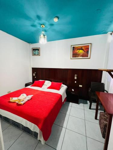 a bedroom with a red bed with a blue ceiling at Hostal Brisas Del Mar in Puerto Villamil