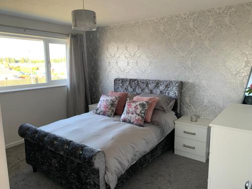 1 dormitorio con cama con almohadas y ventana en SUNNY PRESTATYN APARTMENT, en Prestatyn