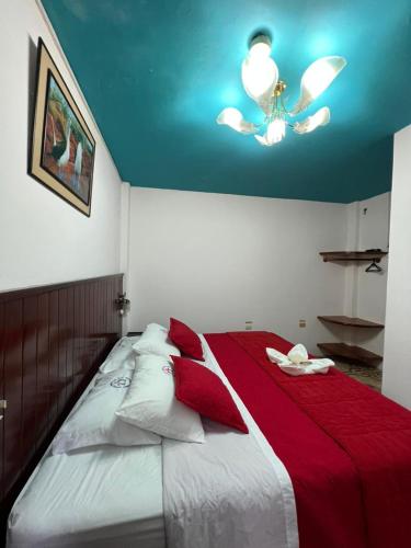 a bedroom with a red and white bed with a ceiling at Hostal Brisas Del Mar in Puerto Villamil