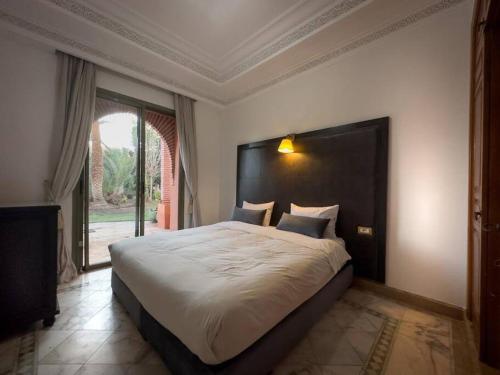 een slaapkamer met een groot bed en een groot raam bij Très joli Appart à la palmeraie coup de cœur in Marrakesh