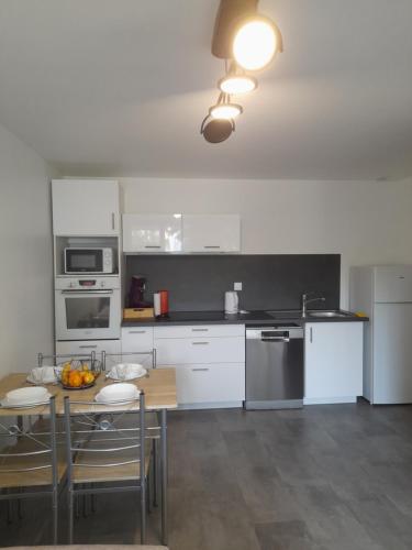 une cuisine avec des armoires blanches et une table avec des chaises dans l'établissement Un doux refuge, à La Roche-sur-Yon