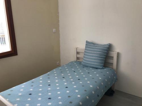 małe łóżko z niebieską kołdrą i poduszką w obiekcie n 3 en face de la gare petite w mieście Roanne