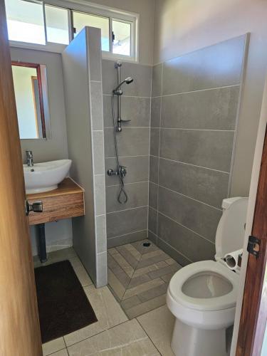 a bathroom with a shower and a toilet and a sink at Miki Miki Surf Lodge in Moorea