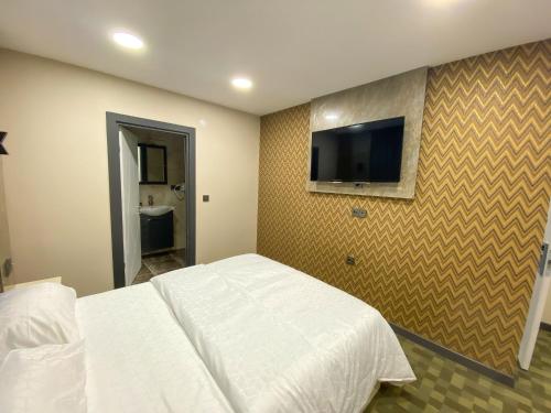 1 dormitorio con 1 cama blanca y TV de pantalla plana en FLORYA EXPRESS OTEL, en Estambul