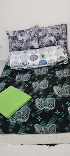 a bed with a comforter with scissors and a green notebook at Matinxs Home in Abu Dhabi