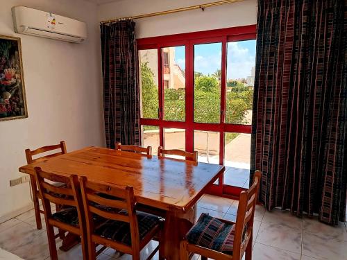 a dining room with a wooden table and chairs and a window at فيلا راقية في منتجع سانتا مونيكا مرسي مطروح عائلات فقط in Marsa Matruh