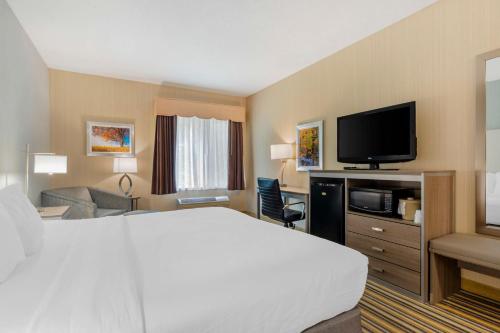 a hotel room with a bed and a flat screen tv at Best Western Plus New England Inn & Suites in Berlin