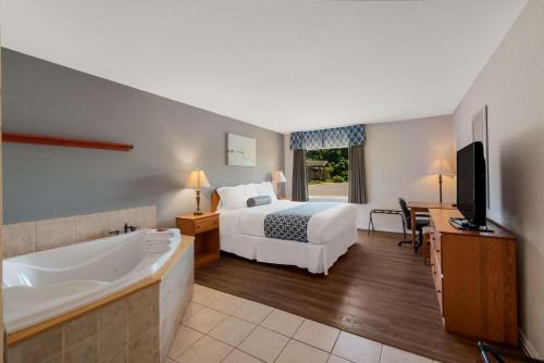 a hotel room with a bed and a tub and a television at SureStay Plus Hotel by Best Western Berkeley Springs in Berkeley Springs
