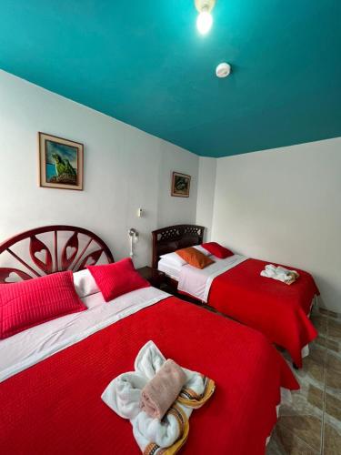 two beds in a room with red and white at Hostal Brisas Del Mar in Puerto Villamil