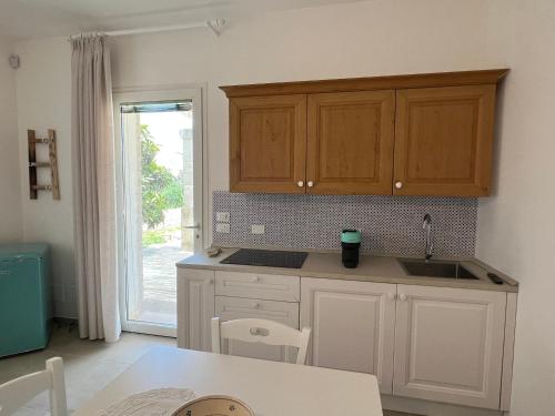 una cucina con armadi bianchi, tavolo e finestra di Bellamora country apartments a Cannole