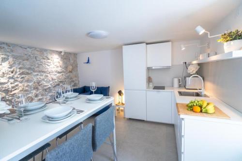 a kitchen with white cabinets and a counter top with fruit on a cutting board at House Franulich in Stara Baška