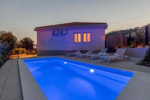 a blue swimming pool in front of a house at Villa KaTess with heated pool in Split