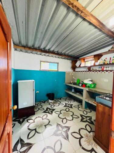 a kitchen with a blue wall and a tile floor at Hostal Brisas Del Mar in Puerto Villamil