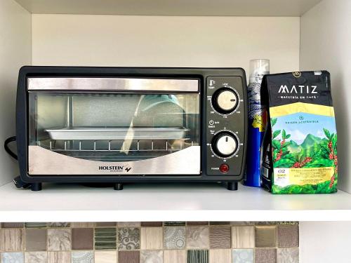 a toaster oven sitting on a shelf next to a book at Lujoso Glamping MarQua Spa Guatavita Wifi Cocina in Guatavita