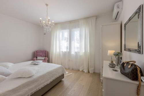 a white bedroom with a bed and a mirror and a chair at Villa KaTess with heated pool in Split